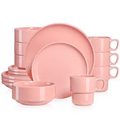 a pink dinnerware set with cups and saucers on the side, in front of a white background