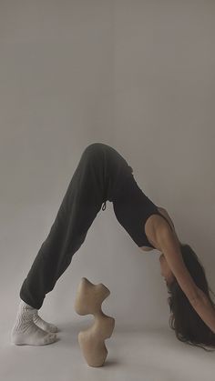 a woman doing a handstand in front of a white wall with three wooden pieces