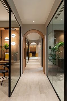 the hallway is lined with glass doors leading to an office area that has a desk and chairs