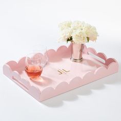 a pink tray with white flowers in it and a glass of wine on the side