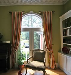 a chair sitting in front of a window next to a book shelf filled with books