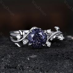 a ring with a blue diamond surrounded by white diamonds on top of a black rock