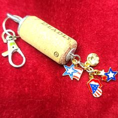 a cork keychain with two charms attached to it on a red velvet surface