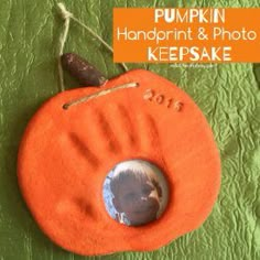 an orange pumpkin shaped photo frame hanging on a green background with the words pumpkin handprint and photo keepsake