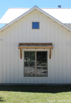 a white building with two windows and a wooden awning