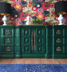 a green dresser with flowers painted on the wall behind it