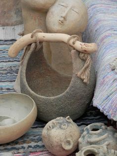 an assortment of pottery is displayed on a colorful cloth covered tablecloth, including a vase and bowl