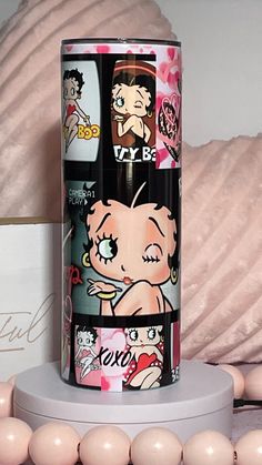 an image of a can with cartoon characters on it next to some beads and pink balls