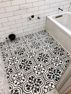 a bathroom with black and white tile flooring next to a bathtub in the corner