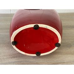 a red vase sitting on top of a wooden table