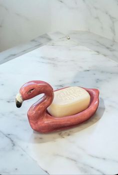 a pink flamingo shaped soap dish sitting on top of a marble counter