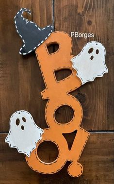 a wooden sign with two ghost heads on it and the word boo spelled in white