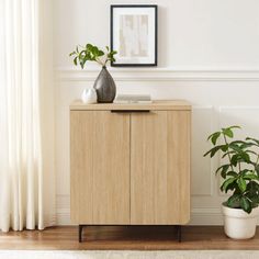 a wooden cabinet sitting next to a potted plant on top of a hard wood floor