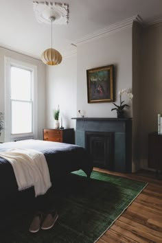 a bedroom with a bed, fireplace and green rug on the floor in front of it