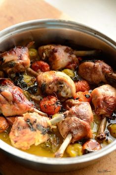 a pan filled with meat and vegetables on top of a wooden table