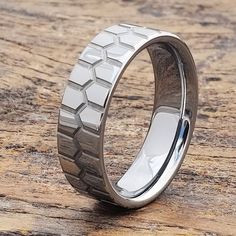 a wedding ring with an unusual design on it's side, sitting on a wooden surface