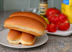 two buns stacked on top of each other in front of some tomatoes and mustard