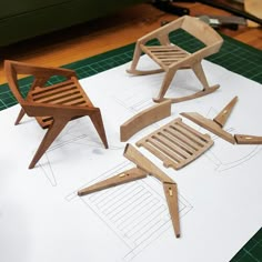 three wooden chairs sitting on top of a piece of paper next to a pair of scissors