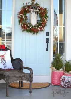 a rocking chair sitting in front of a door with wreaths on it and other decorations