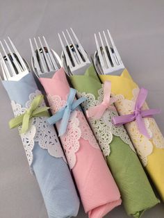 four forks are wrapped in napkins and tied with ribbons on the ends, sitting next to each other