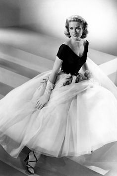 a black and white photo of a woman in a tulle skirt sitting on steps