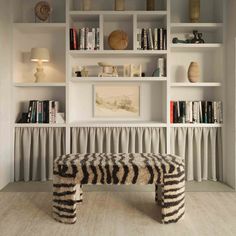 a zebra print bench sits in front of bookshelves with white shelving behind it