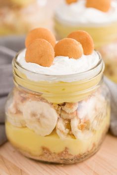 banana pudding in a glass jar with whipped cream and bananas on top, sitting on a wooden table