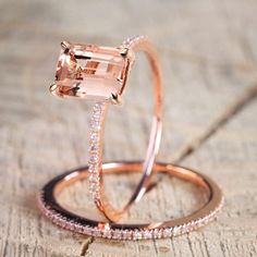 an engagement ring and wedding band set with morganite in rose gold, sitting on a piece of wood