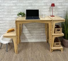 a laptop computer sitting on top of a wooden desk next to a potted plant