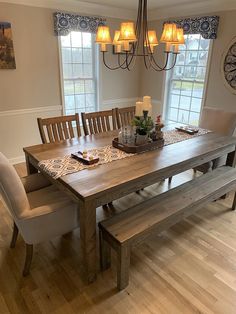 a dining room table with chairs and a bench in front of the window is lit by candles