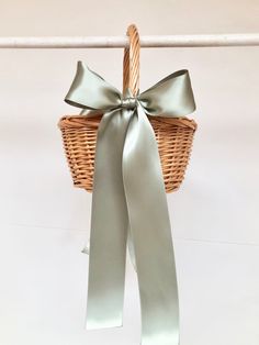 a wicker basket hanging from a clothes line with a ribbon tied around it and another item in the background