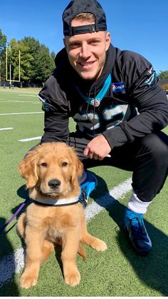 a man kneeling down next to a dog on a field