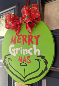 a grinch christmas door hanger hanging on the front door with a red bow