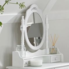 a white dresser with a mirror and candles on it