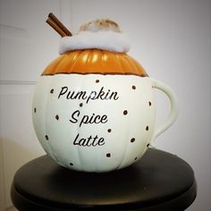 a pumpkin spice latte mug sitting on top of a black table next to a white wall