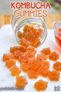 some gummy bears sitting on top of a cutting board next to a glass jar