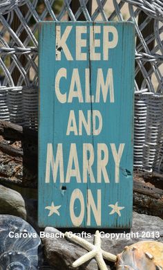 a wooden sign that says keep calm and marry on with starfishs in the background