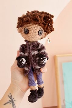 a hand holding a small crocheted doll