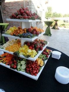 a table topped with three tiered trays filled with fruits and veggies