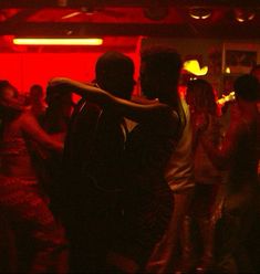 people dancing in a dark room with red lights