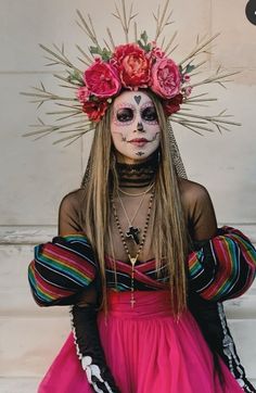 a woman with makeup painted to look like a skeleton wearing flowers in her hair and dress