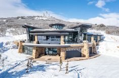 an aerial view of a house in the snow with mountains in the backgroud