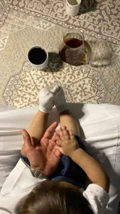 a little boy laying on top of a bed with his hands in the air