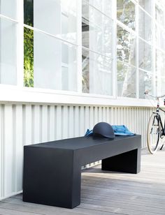 a black bench sitting on top of a wooden floor next to a bike parked in front of a building