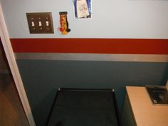 there is a small bed in the corner of this room with red and blue stripes on the walls