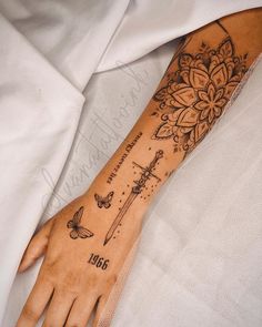 a woman's arm with tattoos on it and butterflies around the wrist, which is decorated with flowers