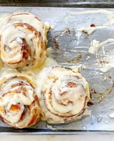 four cinnamon rolls sitting on top of a baking pan