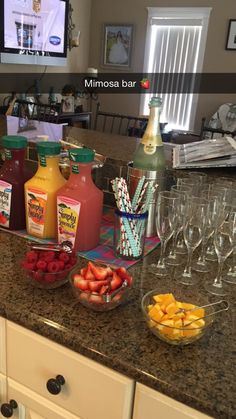 a kitchen counter topped with lots of drinks and fruit next to glasses filled with juice