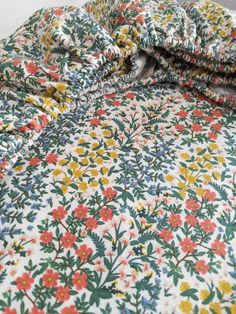 an unmade bed covered with colorful flowers