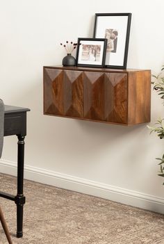 a wooden cabinet sitting on top of a wall next to a chair and potted plant